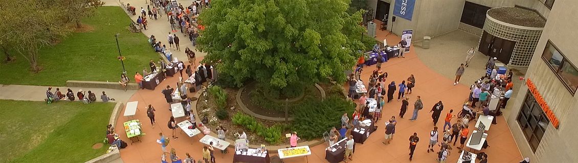 Aerial view of the West Campus main entrance during an event. Lots of students, with display tables set up.