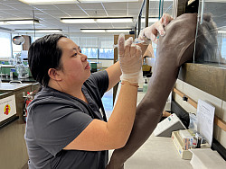 Asian female Nursing student practicing injections into a dummy arm.