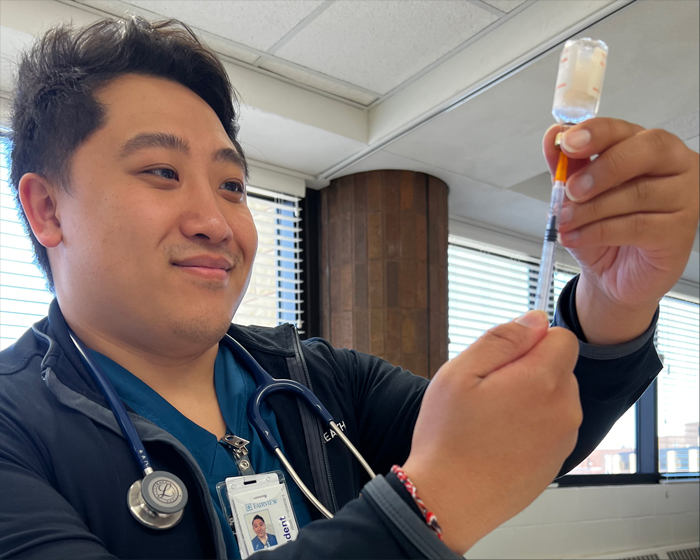 Asian American male nurse filling a syringe.