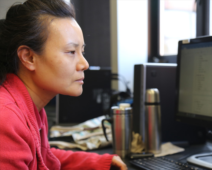 A female wearing a bright red sweater studying at the computer.