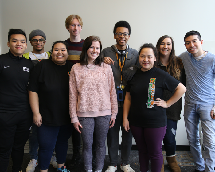 A large, diverse group of students is in the hallway on East Campus.