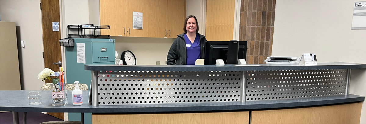 The reception desk at the Dental Clinic with Clinician Lindsay Richison smiling behind the desk.