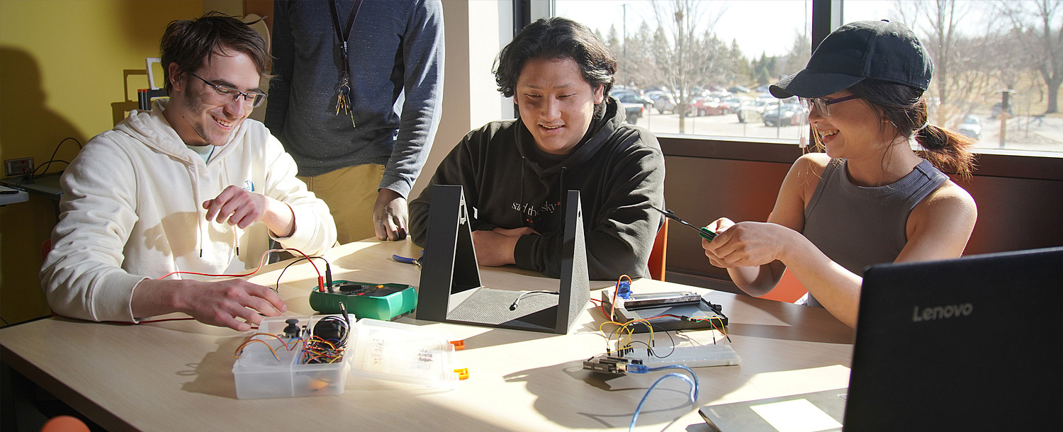 Three engineering students working on rewiring in the classroom.