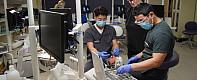 Two students practicing their skills on a test dummy in the dental clinic.