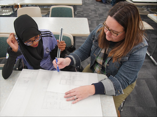 Instructor assisting a student with architectural drawings.