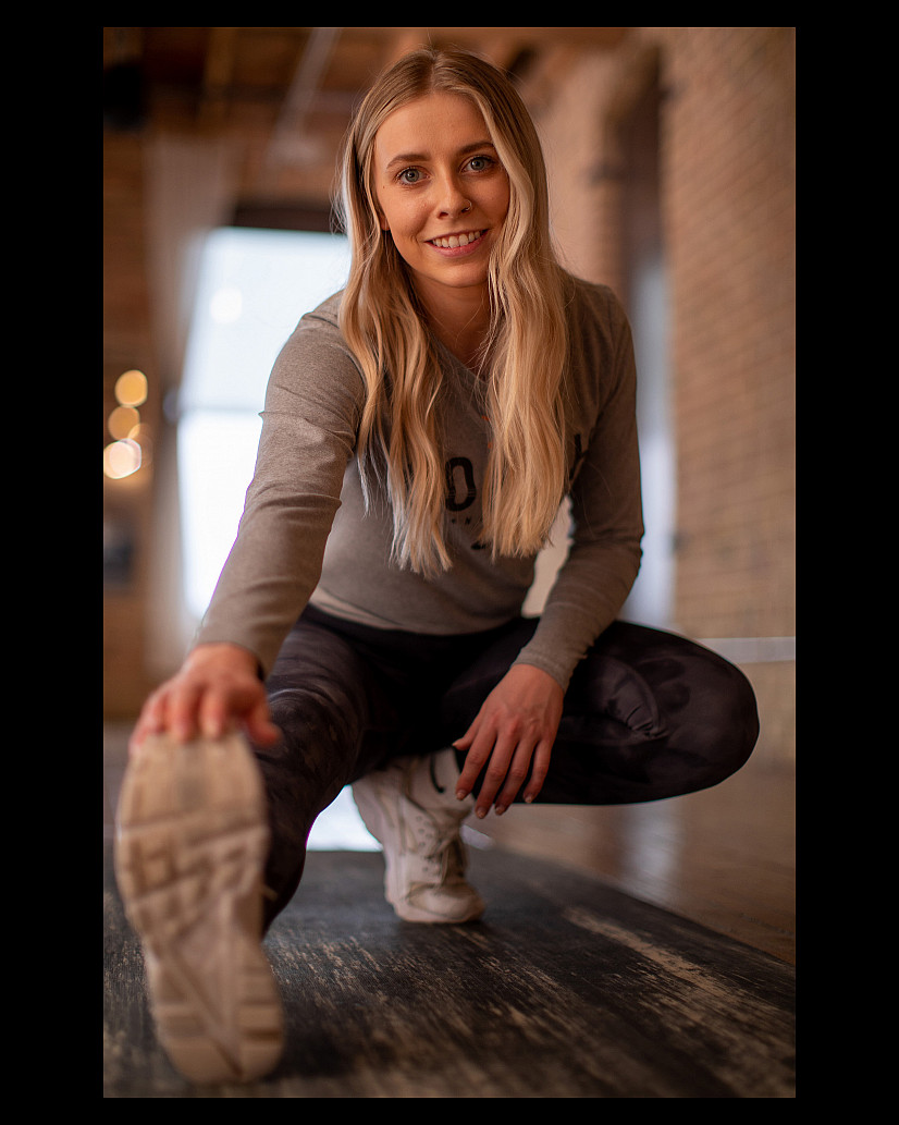 Student photography work. The image captures a female student stretching before a run. She is holding her foot close to the camera and po...